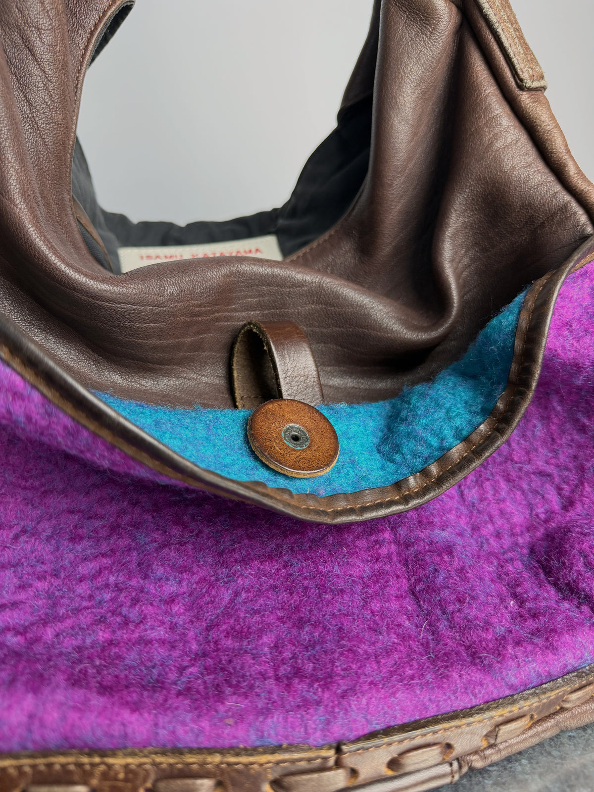 Pocket interior in turquoise felt, leather strap over a stud