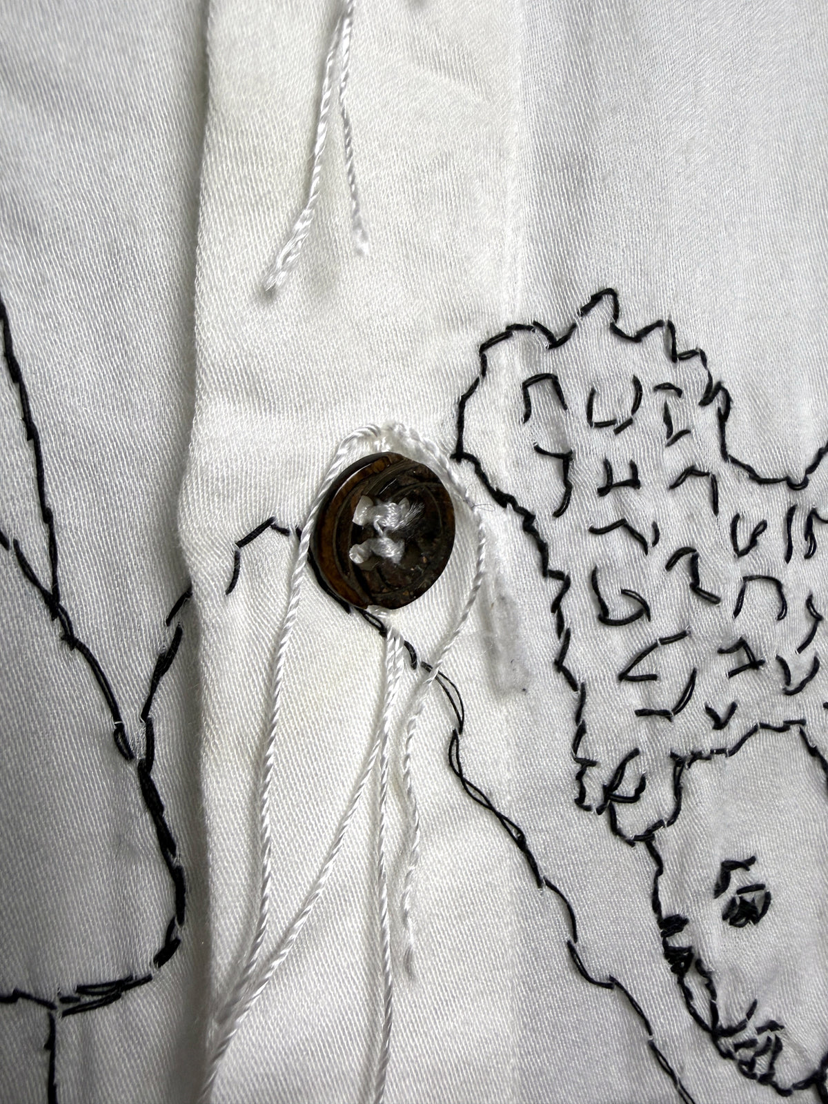 Horn button, sewn with thread left long
